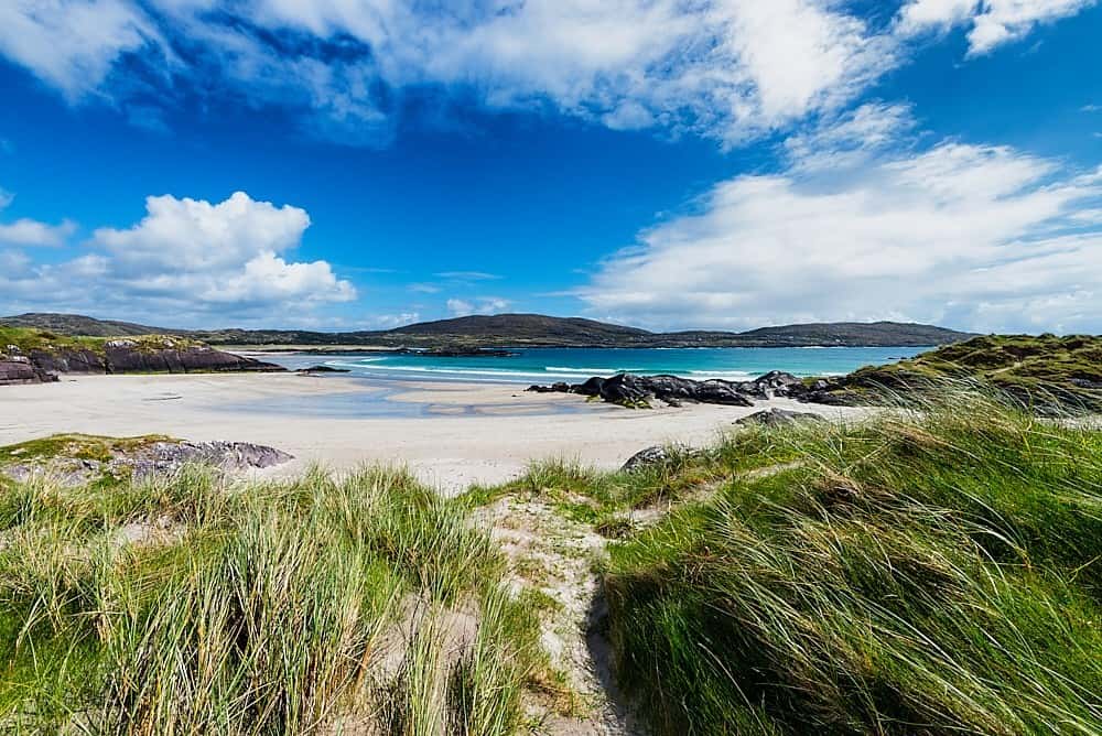 Golden sandy expanse of Derrynane Beach surrounded by rocky outcrops and turquoise Atlantic waters
